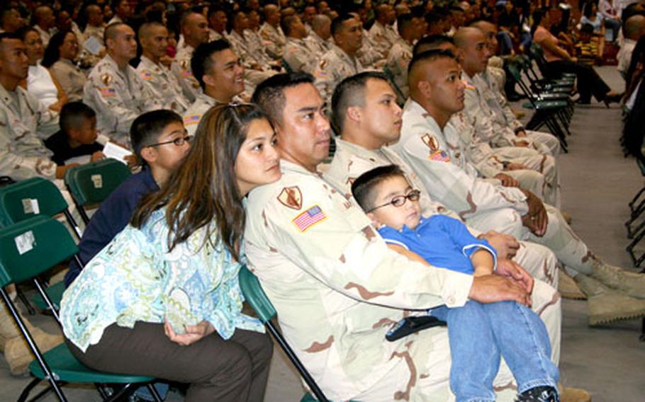 Nicole Napoleon leans on the shoulder of her husband, Spc. Richard Napoleon, of the Guam Army National Guard’s 1st 294th Infantry Battalion, Alpha Company, as he holds son Rylan, 4. Partially obscured by his mother is the couple’s other son, Tyler, 11.