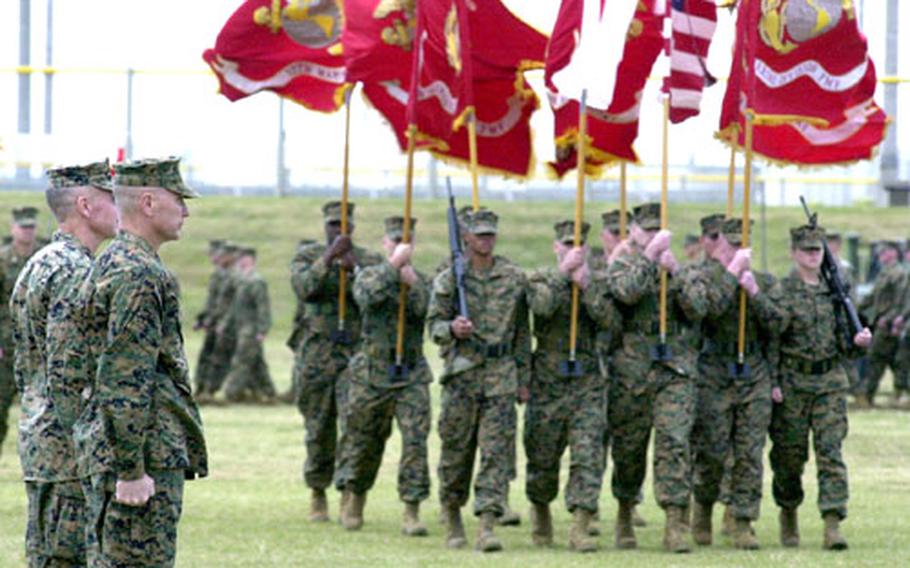 Brig. Gens. Christian Cowdrey, left, and Mastin Robeson stand at attention during a pass in review at their 3rd Marine Division change of command ceremony on Camp Hansen on Wednesday. Cowdrey turned over command of the division to Robeson.