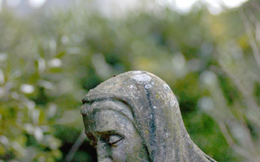 In the back garden of the Church of St. Nicholas, a statue stands among the centuries-old graves. In the background, the towers of Arundel castle rise into the sky.