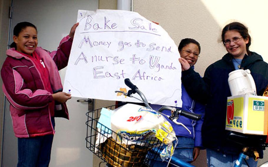 Twelve-year-old twins Norkeshia and Kevneshia Groomes, at left and center, with friend Martha Granderson, 12, at right, sold homemade baked goods Monday and Friday at Marine Corps Air Station Iwakuni to raise money for Granderson’s sister, a nurse, to travel to New Hope, Uganda.