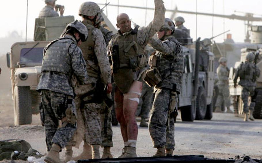 Gunnery Sgt. Michael Burghardt signals his defiance after being struck by an improvised explosive device on Sept. 19 near Ramadi, Iraq. The Marine refused to be carried away on a stretcher and walked under his own power to a waiting medevac. Among those attending to the Marine are Spc. John Adams (far left in front) and Pfc. Darin Nelson.