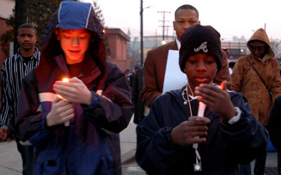 Josh Stephens, left, and Patrick Magee-Williams, both 12, try to keep their candles lit during a walk on Yongsan Garrison on Sunday evening to honor the Rev. Martin Luther King Jr. The event drew more than 200 people to remember King, a leader of the U.S. civil rights movement.