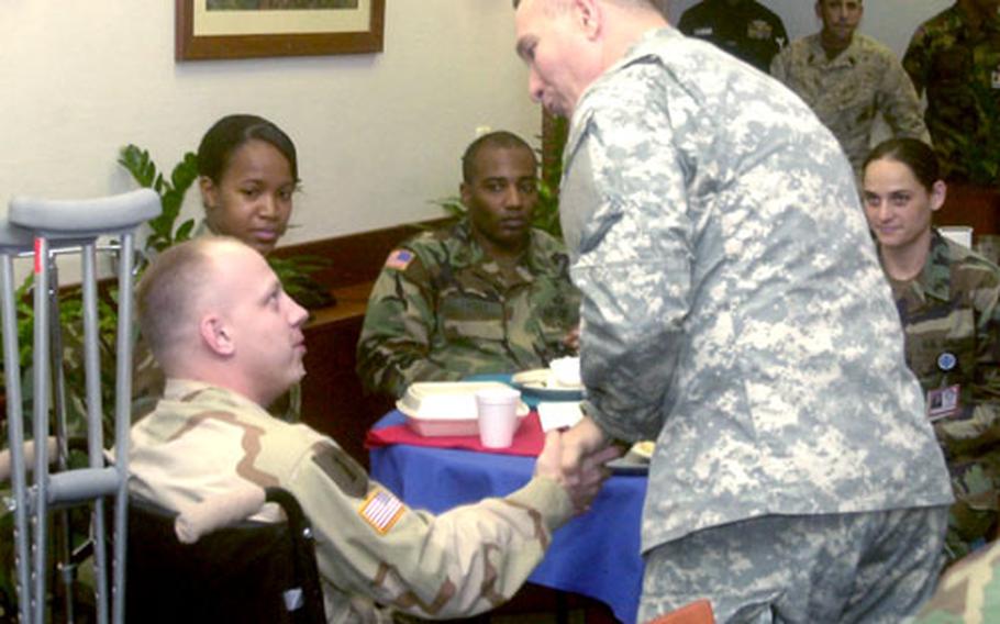 Army Command Sgt. Maj. William Gainey, the first senior enlisted adviser to the chairman of the Joint Chiefs of Staff, right, gives his coin to Army Spc. Christopher Towns at Landstuhl Regional Medical Center on Wednesday.