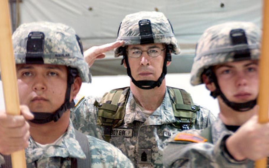 Command Sgt. Maj. Kenneth Boyer, 36th Infantry Division, Texas National Guard, center, salutes during the playing of the national anthem during the transfer of authority ceremony at Camp Bondsteel, Kosovo. On left, Spc. Ambro Aguilar, Task Force Alamo, 36th Infantry Division holds the NATO flag and on right, Spc. Brandon Cox, also of Task Force Alamo, holds the colors from the 40th Infantry Division, the outgoing unit from Kosovo.