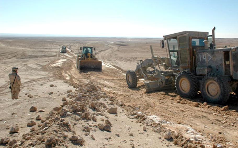 U.S. soldiers use a grader and a loader to construct a new road amid moon-like terrain near Iraq’s border with Syria on Tuesday. The road is due to be completed this spring.