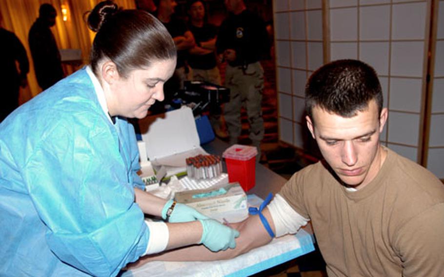 Tech. Sgt. Darcy Ammon draws blood from Staff Sgt. Arthur Bigelow, a 35th Civil Engineer Squadron structural journeyman, during a reintegration briefing at Misawa Air Base, Japan, on Thursday. Bigelow returned with about 70 personnel from Kuwait Wednesday night.