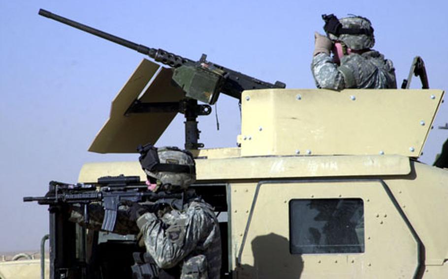 Soldiers from Battery G, 3rd Battalion, 320th Field Artillery Regiment, 101st Airborne Division, use their Humvee as cover while investigating the site of a possible insurgent checkpoint near Tikrit.