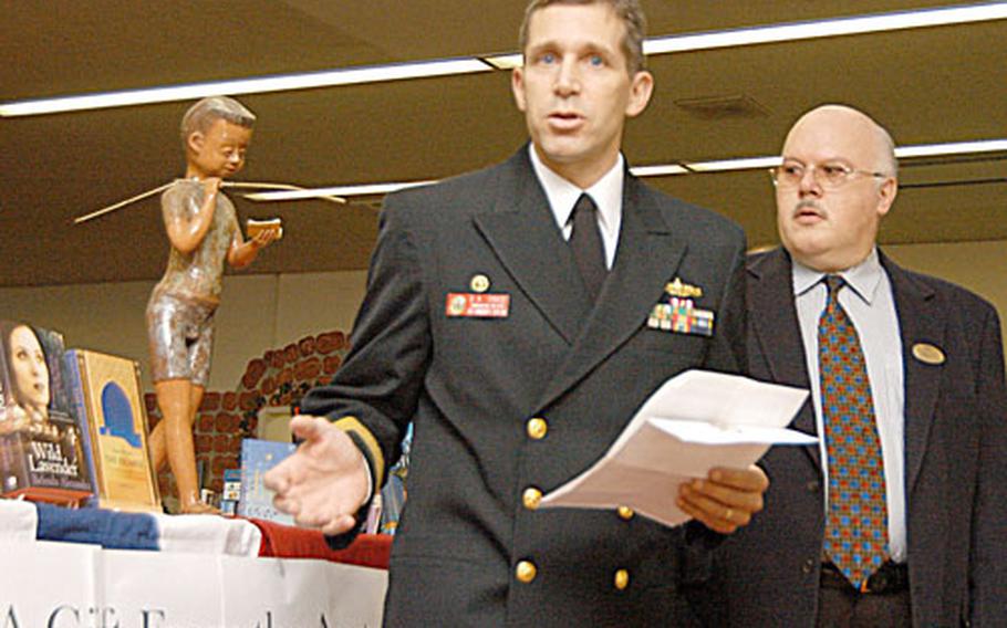 Cmdr. David Chase, USS Vandegrift commanding officer, presented new books by Australian authors to Supervisory Librarian Kevin Jones at Yokosuka Naval Base, Japan, Tuesday.