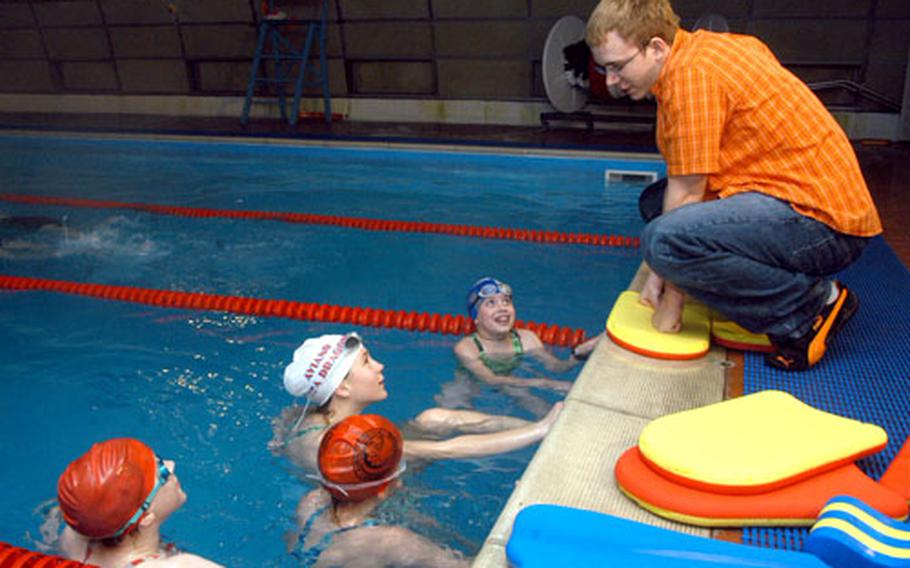 Konrad Korth, right, 16, captain of the Lakenheath Barracuda swimming team, reviews techniques with fellow swimmers during a recent practice. Korth acts as the assistant coach on Wednesdays.