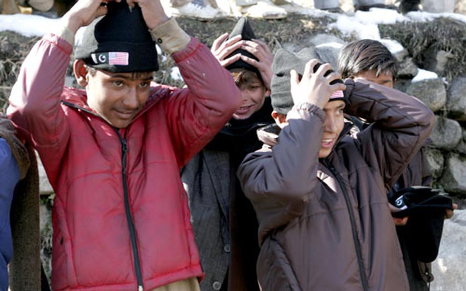 Children in the Seran Valley put on stocking caps given to them Monday by Marines and sailors with Combined Medical Relief Team 3. The CMRT-3 servicemembers handed out portable radios, scarves and stocking caps to the Pakistanis.