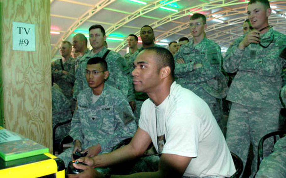 Soldiers watch as Spc. Christian Villanueva and Sgt. Charles Robinson, of the 1st Armored Division, play video games at Camp Buehring, about 25 miles south of the Iraqi border.