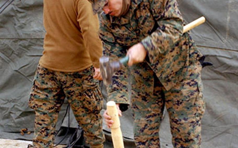 Lance Cpl. Israel Cortes, a radio technician with Marine Wing Support Squadron 171, hammers down a tent stake.