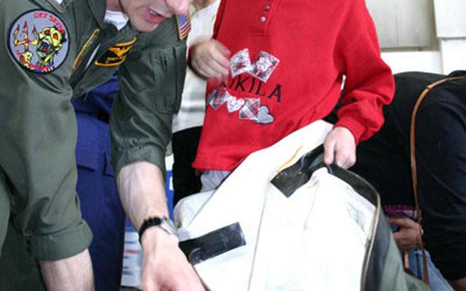 Lt. Bobby Maslar, a C-26 pilot for the U.S. Navy, helps 8-year-old Isabella Cunningham don a "dry" flight suit, a uniform aircrew wear when flying over cold water, during the annual career day at Naples Elementary School.
