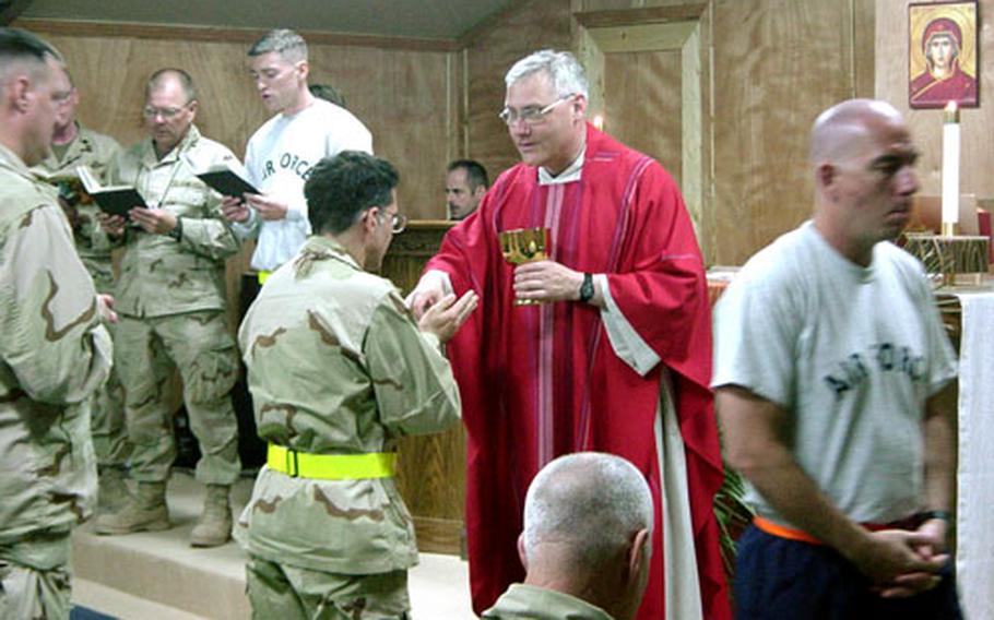 The Rev. Gary Linsky, a lieutenant colonel, Roman Catholic priest and the command chaplain for U.S. Forces Japan, 5th Air Force and 374th Airlift Wing at Yokota Air Base, Japan, gives communion during Mass at Balad Air Base, Iraq.