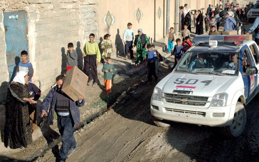 Iraqi police in Tal Afar distribute food and other items offered by U.S. forces as a means of strengthening bonds between local residents and Iraqi security forces recently. The town in northwestern Iraq is being using as an example of the U.S. military’s “oil-spot strategy” of “clear, hold and build.”
