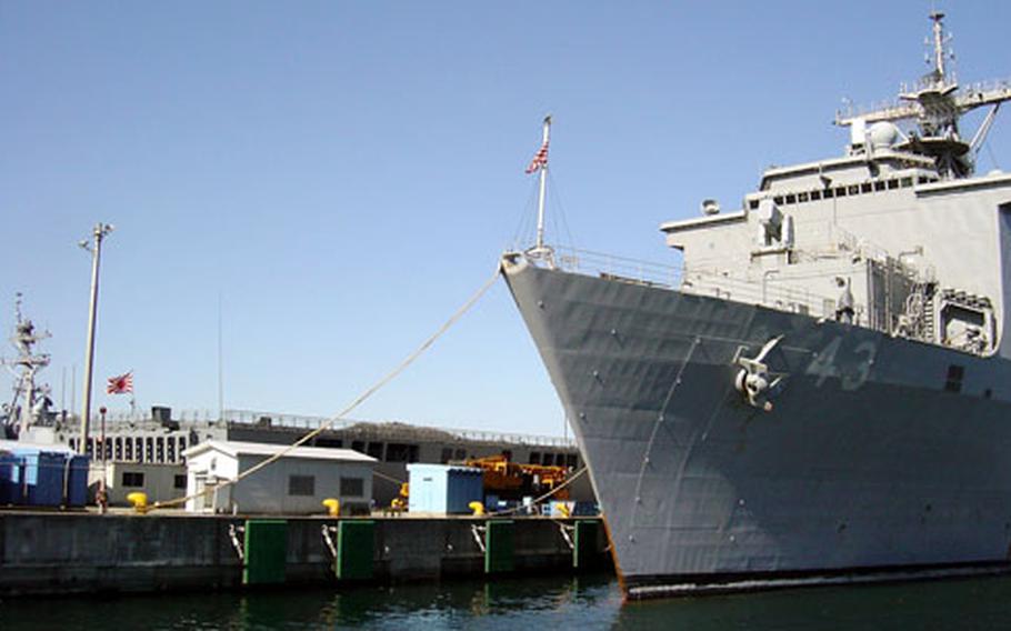 The amphibious dock landing ship USS Fort McHenry, at right, and the Japan Maritime Self-Defense Force ship JDS Ohsumi arrive at Yokosuka Naval Base Sunday.