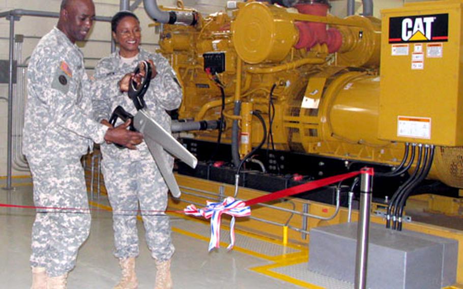Army Col. Edric A. Kirkman, commander of the 516th Signal Brigade, and Lt. Col. Maria R. Drew, commander of the 58th Signal Battalion, prepare to cut the ribbon at Tuesday’s official start-up of a new $11.7 million power plant on Fort Buckner, Okinawa.