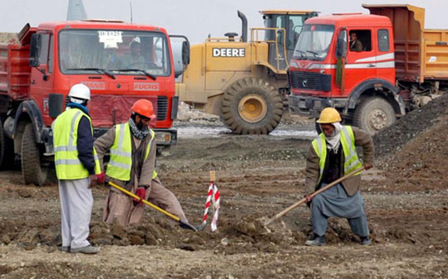 Afghan workers help move dirt as part of the work on a series of projects that will add a second runway and additional ramps to Bagram Air Base in Afghanistan. The new runway should be operational in September, with other parts of the project completed by next spring.