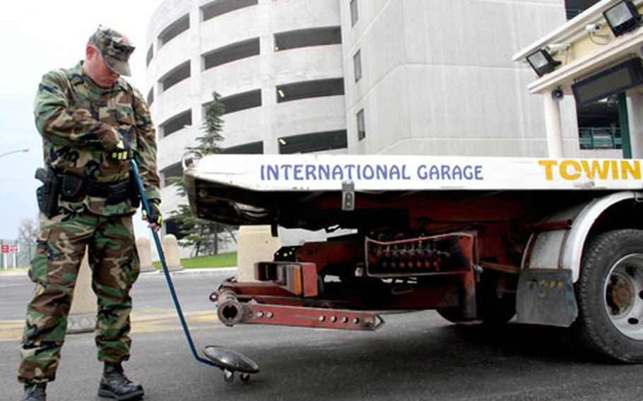 Petty Officer 3rd Class Christopher Darling, 24, scans the undercarriage of a tow truck at Naval Support Activity Naples, Italy. The number of security personnel has steadily decreased over the past few years.