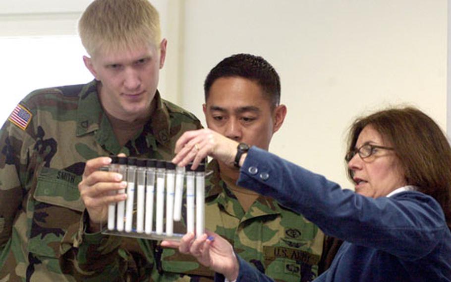 Pfc. Steven Smith, left, and Staff Sgt. Dennis Ladrillono check out the sugar-content display at Baumholder’s first Women’s Health Fair. Most people say “Gross!” when they see how much fat or sugar is in processed foods such as potato chips and soft drinks, said Cathy Douglas, right.