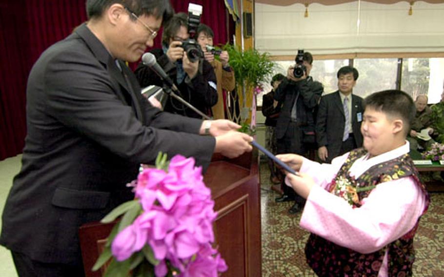 Koo Je-won, right, accepts his elementary school graduation certificate from Tae Sung Dong Elementary School Principal Choi Jong-bok during a ceremony Wednesday in the only South Korean village in the demilitarized zone separating North and South Korea.