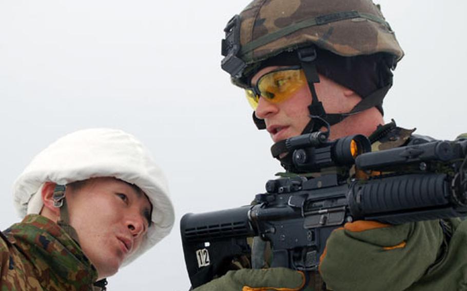 Sgt. Timothy Sides shows the correct technique for close-quarters marksmanship as Sgt. 1st Class Shuji Ohsaka of the Japan Ground Self Defense Force pays close attention during Exercise North Wind ’06 in Camp Iwate, Japan.