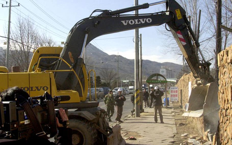 Workers demolish a section of the outside wall near Camp Red Cloud’s main gate at a ceremony Friday in Uijeongbu, South Korea.