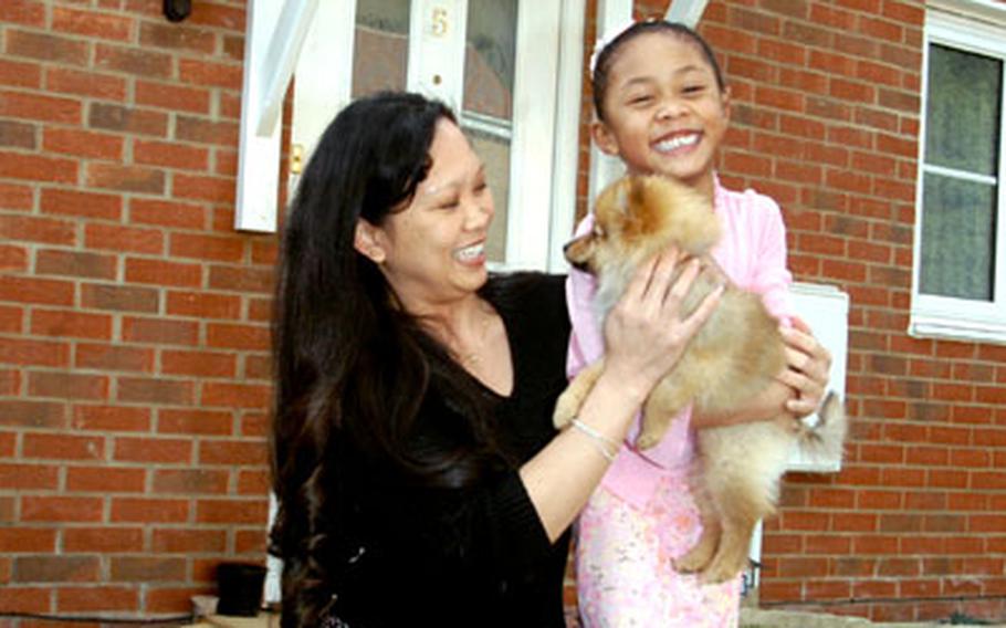 Tech. Sgt. Angela Willis plays with her 6-year-old daughter, Jade, and their dog, Sheba, in front of the semi-detached house that she bought in Beck Row.