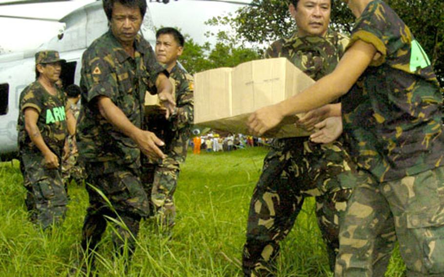 Soldiers from the Republic of the Philippines Army offload food, blankets, water and other vital supplies in St. Bernard, Philippines, from a CH-46E Sea Knight helicopter assigned to the Flying Tigers of Marine Medium Helicopter Squadron 262.