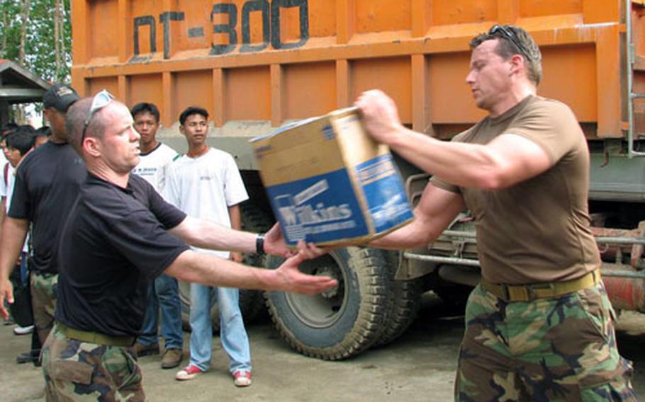 Capt. Charles Brisbois, left, hands a case of water to Capt. Mark Van Weezendonk during humanitarian relief operations in southern Leyte. Both are from the 31st Rescue Squadron stationed at Kadena Air Base, Okinawa. The 18 pararescuemen and combat rescue officers on the scene are medics specially trained for confined-space rescue, adverse terrain and mountain climbing operations.