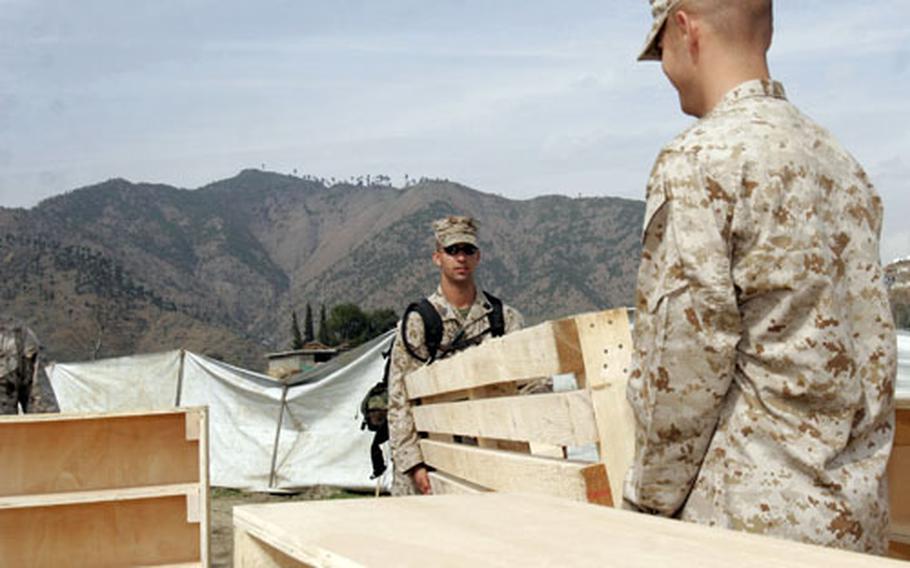 Seaman Jonathan F. Casale, left, and Lance Cpl. Keith A. Post unload furniture at the Seran Sialkot Tent Village in Daryal, Pakistan. Servicemembers from the Okinawa-based Combined Medical Relief Team 3 recently built and donated benches, shelves, computer tables, exam tables and floor decking to a clinic in the village.