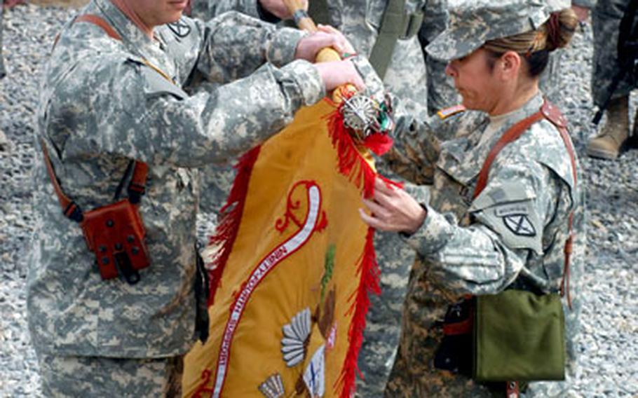 Lt. Col. Michael Howitz, commander of the 94th Brigade Support Battalion, left, and Command Sgt. Maj. Ofelia Webb unfurl the unit’s colors at a transfer of authority ceremony Saturday at Kandahar Airfield in Afghanistan. It’s the first time the unit’s guidon has been displayed overseas since Vietnam.