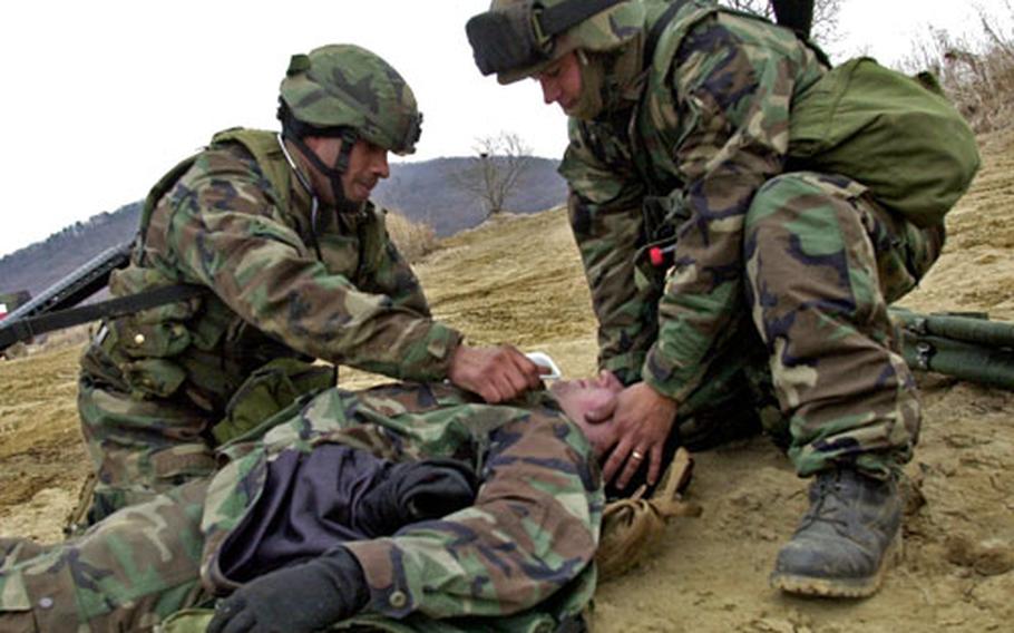 Staff Sgt. Duran Wilson, left, and Sgt. Todd Vance treat a simulated casualty during a field medical scenario at Warrior Base, South Korea, on Tuesday.