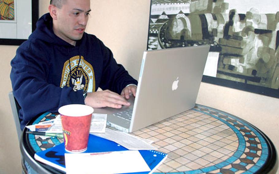 Petty Officer Markus Ramirez, a cook from the crew of the USS Essex, connected to free wireless Internet service Thursday at Wolfgang Puck’s Café in the Harbor View Club at Sasebo Naval Base to pay his monthly bills while enjoying some hot coffee.
