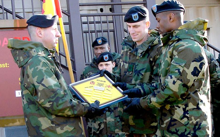 Col. John Rossi, left, presents a plaque to Capt. Brian Moore, center, and 1st Sgt. Michael Hudson, both of Headquarters and Headquarters Battery, at Osan Air Base, South Korea, on Friday.