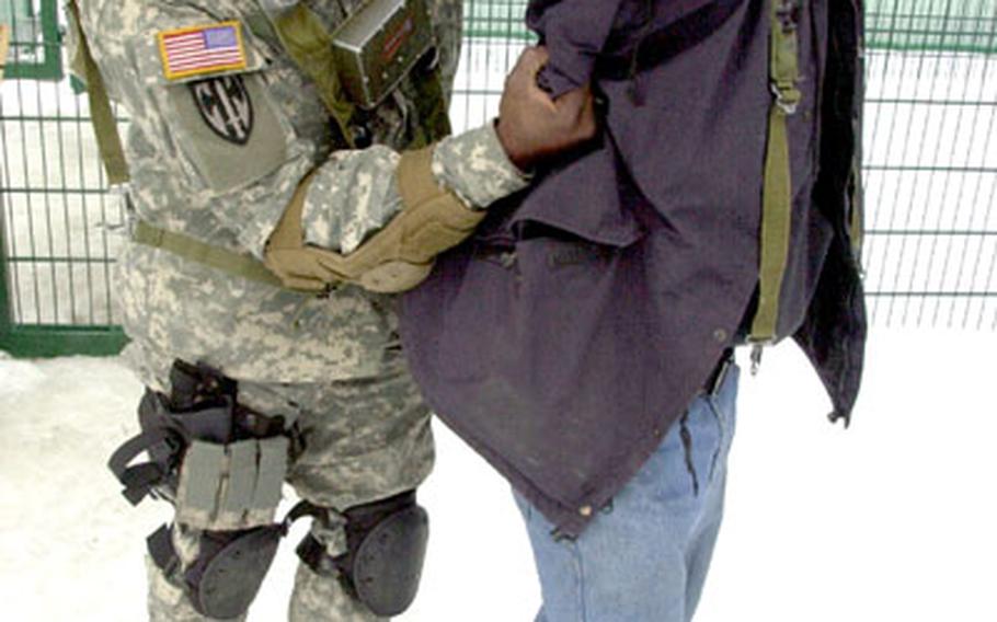 Sgt. Chris Simmons, 38, of the 2nd Platoon, 1st Military Police Company, left, escorts Spc. Willie Ruiz, 21, of Patterson Cal. into the Brigade Consolidated Collection Point at Hohenfels, Germany, on Monday. Ruiz, playing the role of an insurgent, was captured by 2nd Brigade Combat Team, 1st Infantry Division soldiers training to deploy to Iraq later this year.