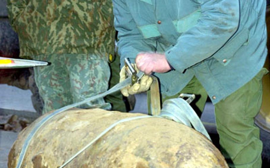 Frank Brombach, from a German bomb removal team, secures a 1,000-pound, U.S. bomb for removal Wednesday evening on the Air Force's Vogelweh Housing Area in Kaiserslautern, Germany. Discovered by construction crews Monday, the bomb was defused and removed safely Wednesday evening.