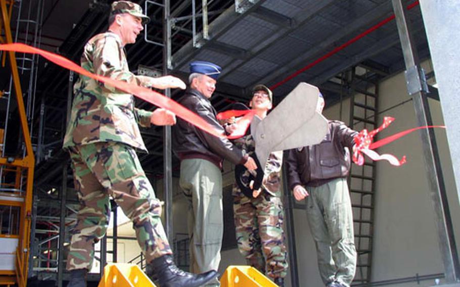 Gen. Duncan McNabb, commander of the Air Mobility Command, center left, and Brig. Gen. Robert McMahon, director of logistics, Headquarters Air Mobility Command, wield the scissors at Tuesday’s ribbon-cutting, as Col. Jeff Worthing, commander of the 733rd AMS, looks on. Hidden by the scissors is Col. Jeffrey Kennedy, vice commander of Kadena’s 18th Wing.