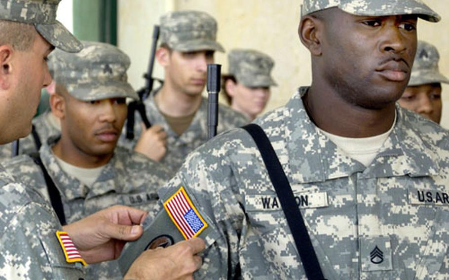V Corps Capt. Gareth R. Lintt, left, commander of Headquarters and Headquarters Company, Multi-National Corps/Force-Iraq, places the new combat patch on V Corps’ Staff Sgt. Sheldon Watson of the MNC-I Civil Affairs division.