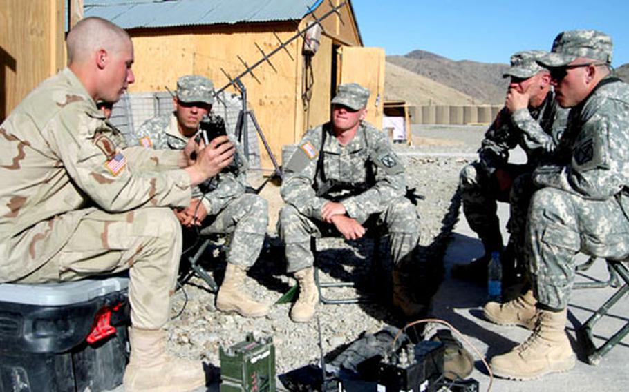 Spc. Jason Slomiak of 3rd Platoon, Company B, 2nd Battalion, 503rd Infantry Regiment, 173rd Airborne Brigade goes over communications equipment with soldiers of 1st Platoon, Company A, 2nd Brigade, 4th Infantry Regiment, 4th Brigade, 10th Mountain Division at Forward Operating Base Arghandab, Afghanistan.