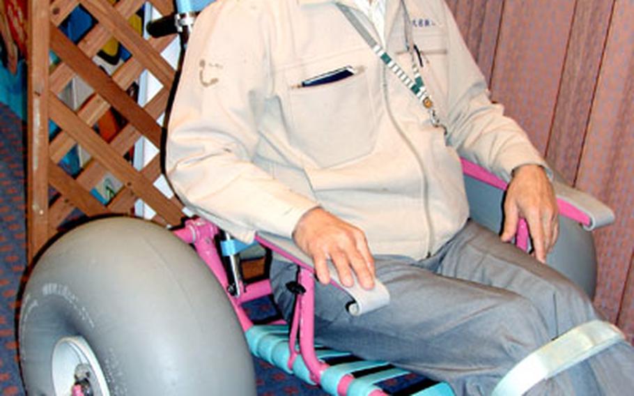 Soichi Shimabukuro shows off his invention, an amphibious wheelchair, during the 2006 Okinawa business Fair.