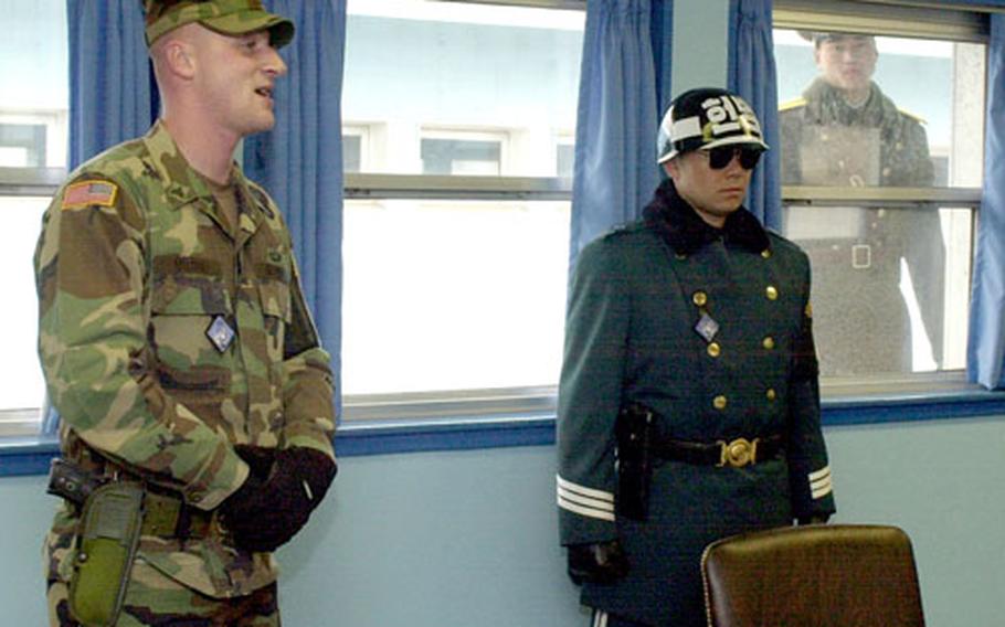 A curious North Korean soldier, right background, peeks in on a distinguished visitor tour given by security escort Sgt. John Dotson, left, at the Joint Security Area recently.
