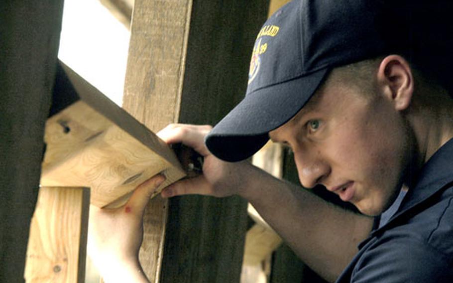Seaman Devin Devine, stationed on the USS Emory S. Land, measures planks Wednesday for a schoolhouse window at Port Gentil, Gabon, along the Gulf of Guinea.