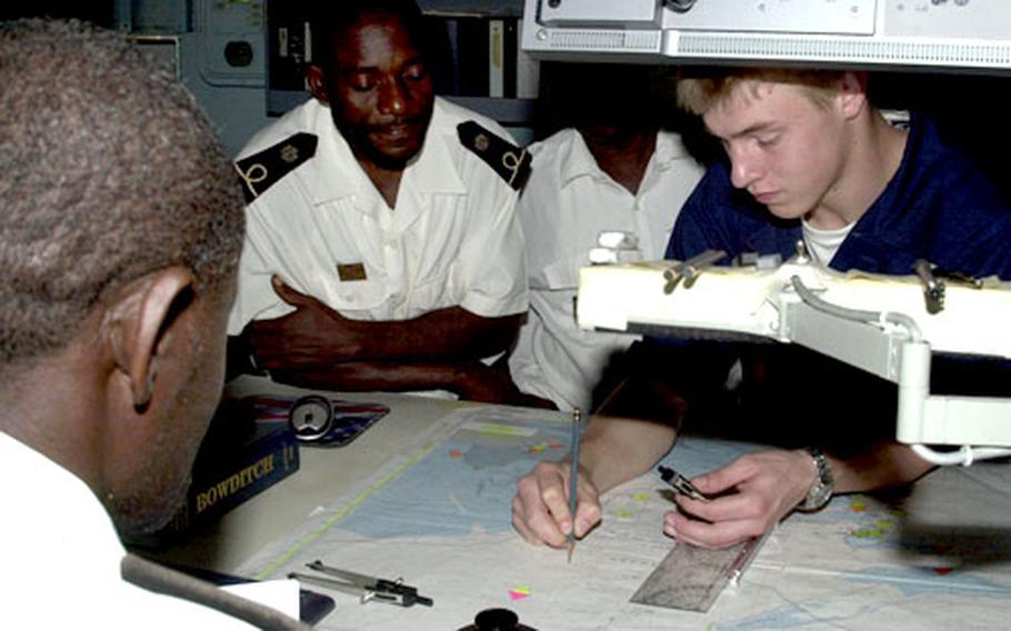 Seaman Timothy Ensley compares navigational aids with members of the Gabonese navy Wednesdsay on the bridge of the USS Emory S. Land, moored in Port Gentil, Gabon.