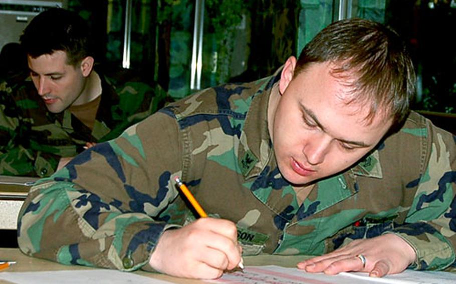 Petty Officer 2nd Class Thomas Sorenson, foreground, and Petty Officer 2nd Class Kevin Tibbets take the first class petty officer examination March 2 at the Navy Club.