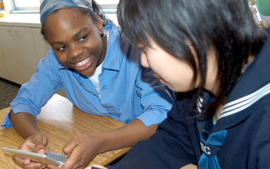 Kenya Jenkins, left, a ninth-grader at Edgren High School on Misawa Air Base, Japan, looks at a digital English-Japanese translator with Chisato Terashita on Tuesday.