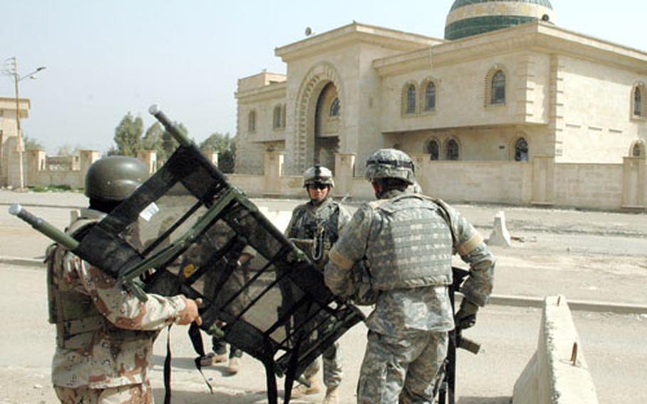 U.S. and Iraqi troops ready a stretcher to transport an Iraqi soldier who was wounded in a drive-by shooting in Baghdad last week.