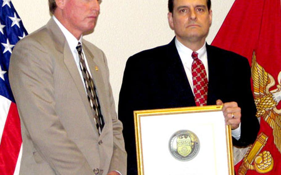 Thomas A. Betro, right, director of the Naval Criminal Investigative Service, presents the agency’s first-ever Meritorious Unit Citation to Kevin Naylon, resident agent in charge of the NCIS Okinawa Resident Agency. The award was for the agency’s quick work in solving the murder of a Navy dental technician on Camp Hansen last year.