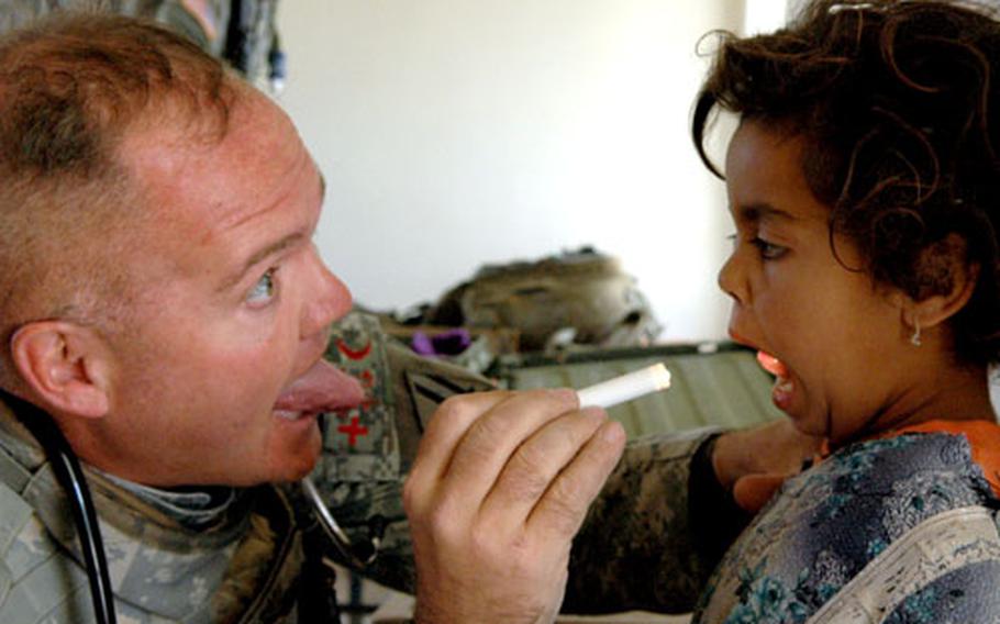 Medic Todd Cole asks an Iraqi girl to stick her tongue out during a medical exam during a civil affairs health mission near Camp Scania recently.