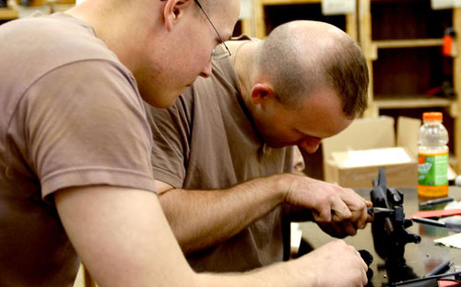 Pfc. Dustin Shugren, left, of St. Francis, Minn., and Spc. Kurtis King, of New Lexington, Ohio, both with the 322nd Maintenance Company, work on a weapon at the small-arms repair shop at Camp Anaconda, Iraq.